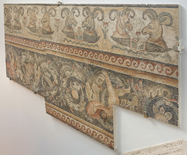 Border fragment of floor mosaic depicting rams' heads over open wings